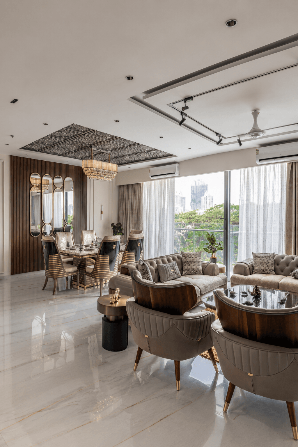 Luxury living and dining room with a statement chandelier and gold-accented furniture